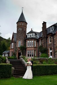 Bride and Groom stood in front of The Torridon Hotel, Loch Torridon, Scotland